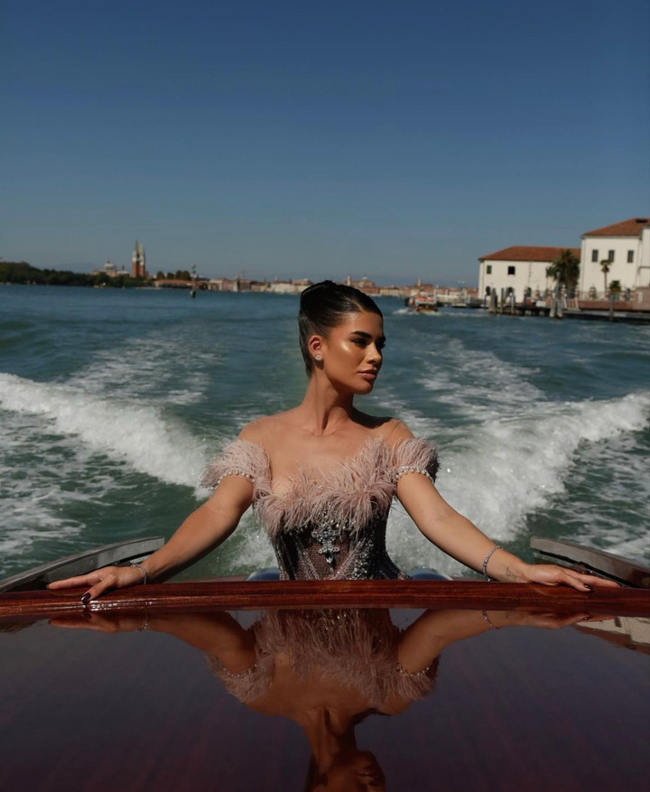 Vanessa Borelli chọn chiếc đầm trễ vai với phần long vũ tạo điểm nhấn. Thân váy chất liệu cao cấp tạo độ rủ và hiệu ứng lấp lánh, khiến người đẹp thành danh trong lĩnh vực, thời trang, làm đẹp và phong cách sống trở thành tâm điểm trước mọi ống kính.