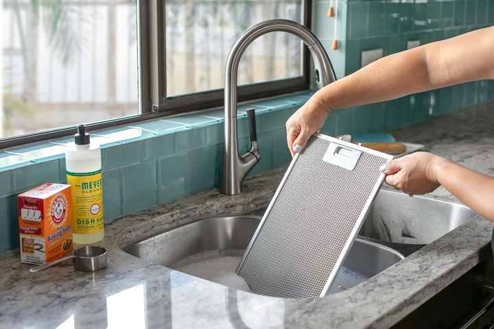 Ngâm tấm lọc máy hút mùi trong dung dịch tẩy rửa. (Ảnh: Thekitchn)