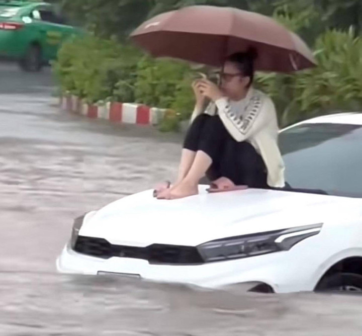 Hình ảnh chị K. C. ngồi trên nắp capo giữa "biển nước".