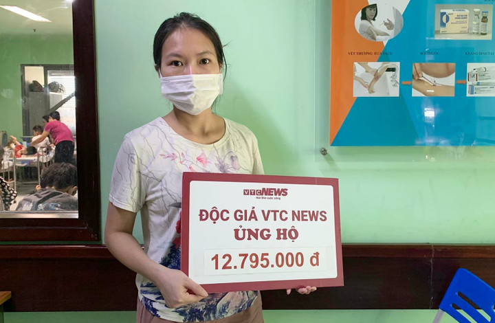 Đại diện gia đình bé Phạm Gia Huy đón nhận số tiền ủng hộ từ bạn đọc.