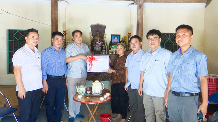 Chủ tịch UBND huyện Thường Tín Nguyễn Xuân Minh (đứng thứ 3 từ trái sang) thăm hỏi, tặng quà bà Vũ Thị Thíu, con liệt sỹ Vũ Bá Chức.