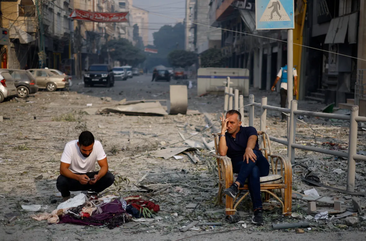 Người dân thành phố Gaza ngồi trên một con đường vừa bị không kích.