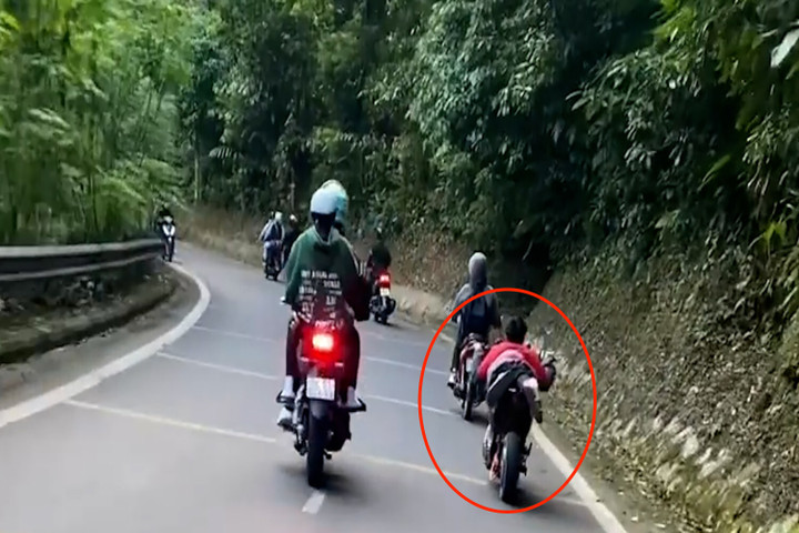 Nam thanh niên không đội mũ bảo hiểm, nằm rạp trên yên xe máy điện, vít ga trên cung đường đèo.