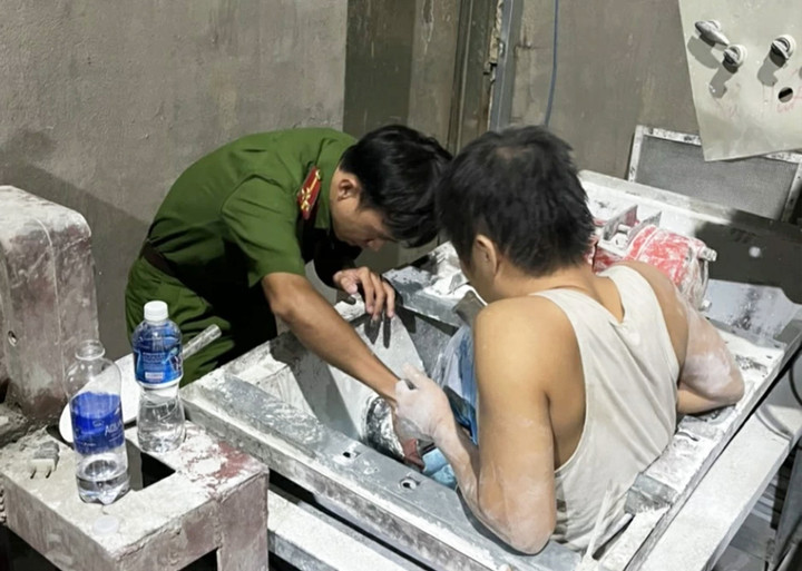 Cảnh sát giải cứu nam công nhân kẹt trong máy trộn xi măng. (Ảnh: Đ.T)