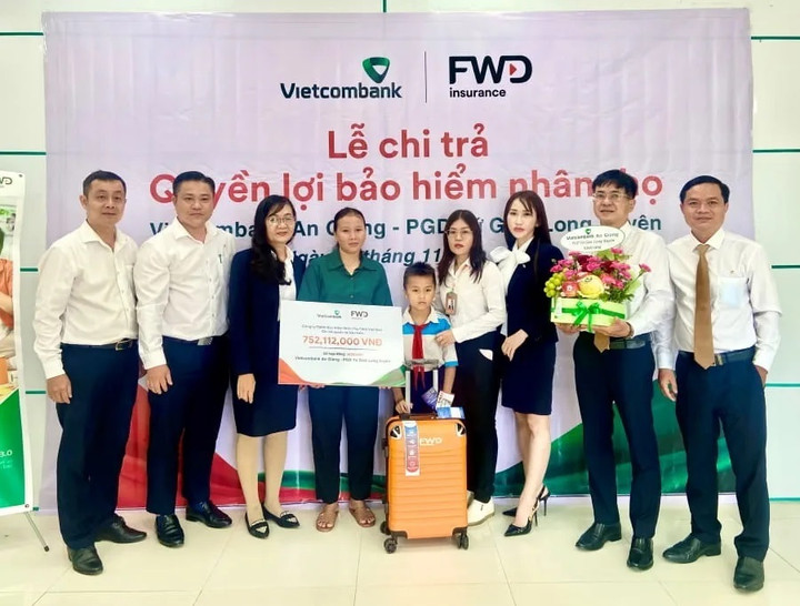 Đại diện Vietcombank An Giang, bà Dương Thoại Uyên - Phó Giám đốc (thứ 3 từ trái sang) cùng đại diện các tổ chức đoàn thể chi nhánh trao bảng chi trả quyền lợi bảo hiểm cho khách hàng.
