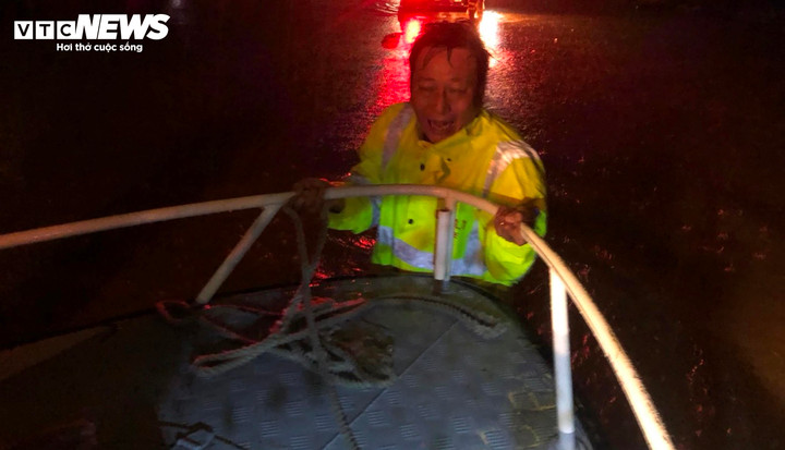 Cán bộ CSGT dầm mình trong nước lụt để đẩy ca nô tiếp cận người dân gặp nạn.