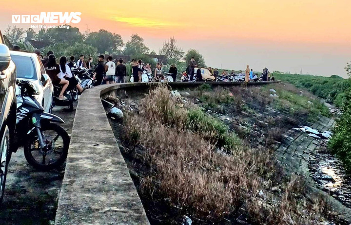 Người dân tụ tập tại bờ đê cạnh rừng bần để theo dõi vụ việc. Ảnh chụp chiều 7/12.