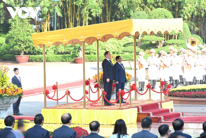 Hai nhà lãnh đạo bước lên bục danh dự. Quân nhạc lần lượt cử quốc thiều hai nước.