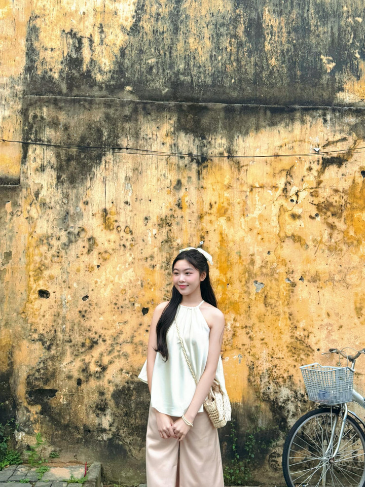 Lọ Lem diện áo yếm màu trắng và quần dáng suông khoe vóc dáng mảnh mai cùng bờ vai nuột nà.