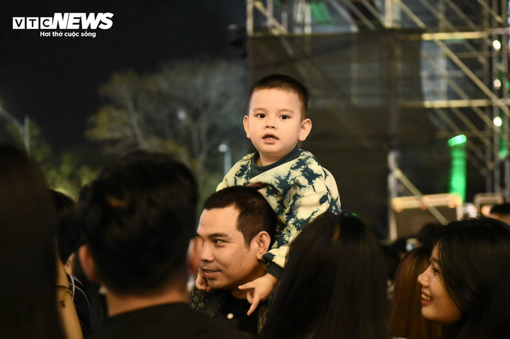 Một em nhỏ được bố cõng trên vai chen lấn giữa dòng người trên phố đi bộ Hồ Gươm