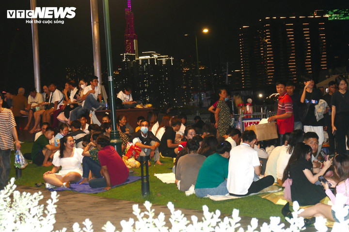 Nhiều người ngồi kín các bãi cỏ tại công viên bến Bạch Đằng (quận 1, TP.HCM) để chờ xem pháo hoa. Đây là được coi là nơi có tầm ngắm đẹp nhất để thưởng thức pháo hoa chào năm mới 2024.