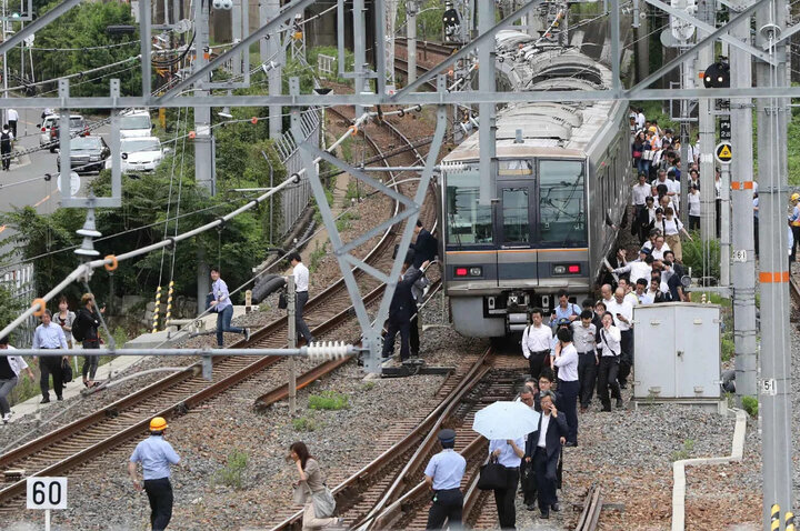 Hành khách đi bộ dọc theo đường ray sau trận động đất vào ngày 18/6/2018 ở Osaka. (Ảnh: AFP)