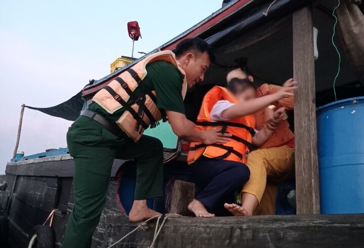 Bé gái con anh Khánh được cán bộ biên phòng đưa lên một chiếc thuyền khác để vào bờ.