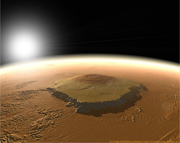 Olympus Mons là ngọn núi lửa hùng vĩ nhất trong Hệ mặt trời. Nằm trong vùng núi lửa Tharsis, nó có kích thước tương đương với bang Arizona, Mỹ, theo NASA. Chiều cao của nó là 25 km, gần gấp ba lần chiều cao của đỉnh Everest trên Trái đất, vốn cao chỉ khoảng 8,9 km. Olympus Mons là một ngọn núi lửa hình khiên khổng lồ, được hình thành sau khi dung nham đổ từ từ xuống sườn núi. Điều này có nghĩa là ngọn núi có thể dễ dàng leo lên đối với những nhà thám hiểm trong tương lai, vì độ dốc trung bình của nó chỉ khoảng 5%. Tại đỉnh có một vùng trũng ngoạn mục rộng 85 km, được hình thành bởi các khoang magma bị mất dung nham. (Ảnh: NASA/Nhóm khoa học Mola/ O. de Goursac, Adrian Lark)