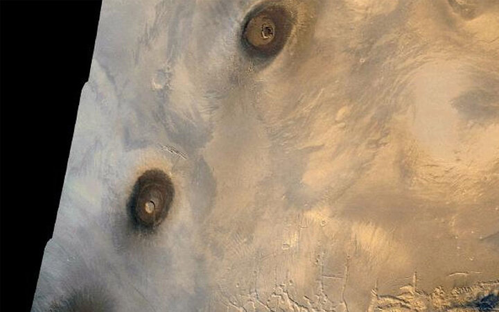 Trong khi leo quanh Olympus Mons, du khách cũng nên nán lại để quan sát một số ngọn núi lửa khác ở vùng Tharsis. Theo NASA, Tharsis có 12 ngọn núi lửa khổng lồ trong một khu vực rộng khoảng 4.000 km. Giống như Olympus Mons, những ngọn núi lửa này có xu hướng lớn hơn nhiều so với những ngọn núi lửa trên Trái đất. Chúng có thể đã phun trào trong khoảng thời gian cách đây khoảng hai tỷ năm trước. Hình ảnh này cho thấy khu vực phía đông vùng Tharsis, do tàu Viking 1 chụp vào năm 1980. Ở bên trái, từ trên xuống dưới, bạn có thể thấy ba ngọn núi lửa hình khiên cao khoảng 25 km: Ascraeus Mons, Pavonis Mons và Arsia Mon. Ở phía trên bên phải là một ngọn núi lửa hình khiên khác có tên là Tharsis Tholus. (Ảnh:NASA/JPL)