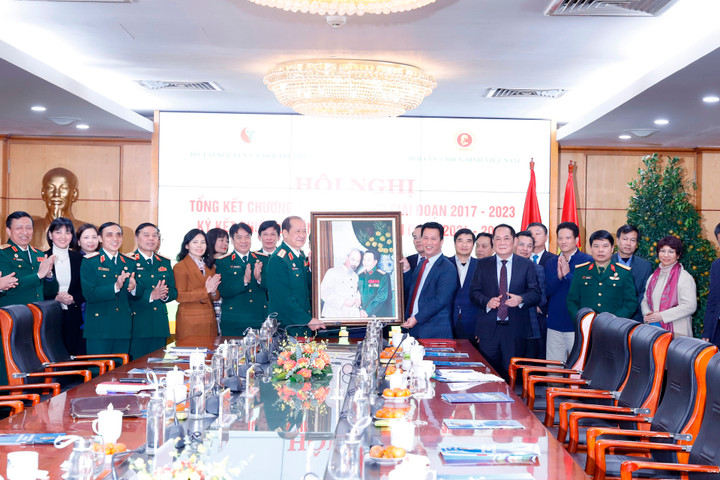 Bộ trưởng Đặng Quốc Khánh cùng Thượng tướng Bế Xuân Trường và các đại biểu chụp ảnh lưu niệm bên bức tranh Chủ tịch Hồ Chí Minh và Đại tướng Võ Nguyên Giáp.