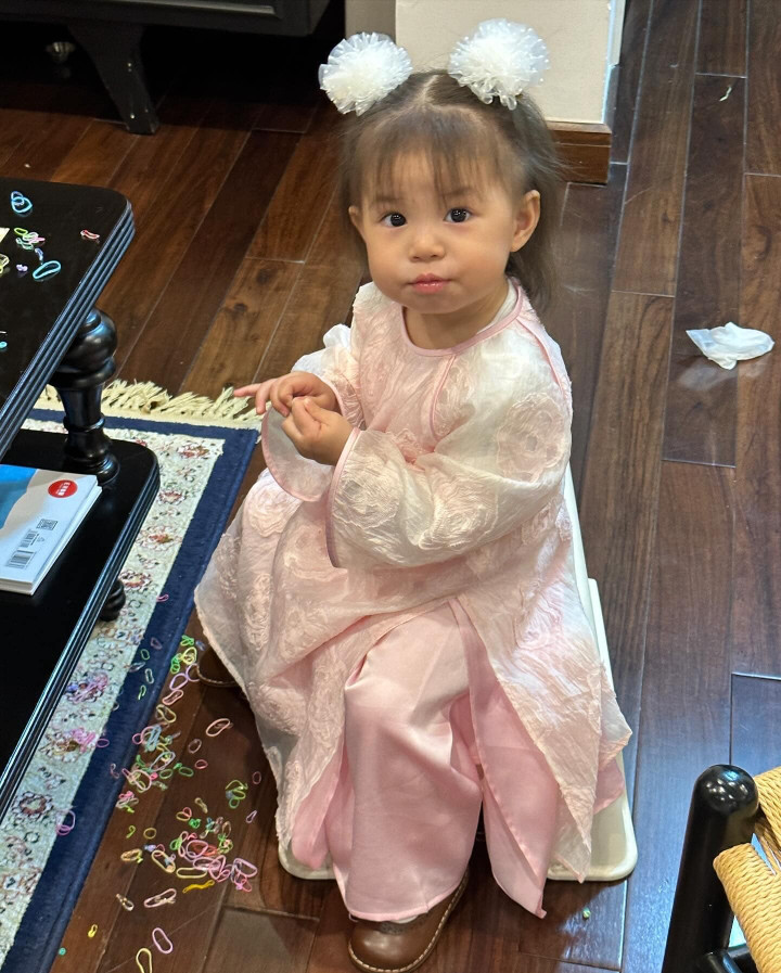 Chuẩn bị đón giao thừa, Pam diện áo dài họa tiết hoa in nổi và chất liệu xuyên thấu nhẹ nhàng. Mẹ Salim còn còn phối thêm cho bé 2 chiếc nơ buộc tóc màu trắng xinh xắn.