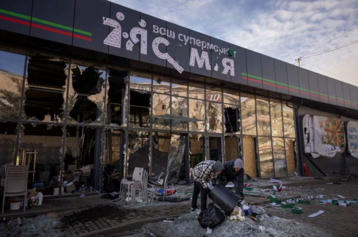 Người dân địa phương dọn dẹp các mảnh vỡ từ một siêu thị bị hư hại ở Ukraine. (Ảnh: Reuters)