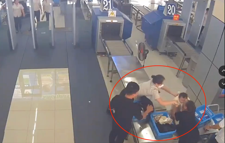 Nữ nhân viên an ninh sân bay kịp thời đỡ cháu bé ngã từ trên bàn. (Ảnh cắt từ clip)