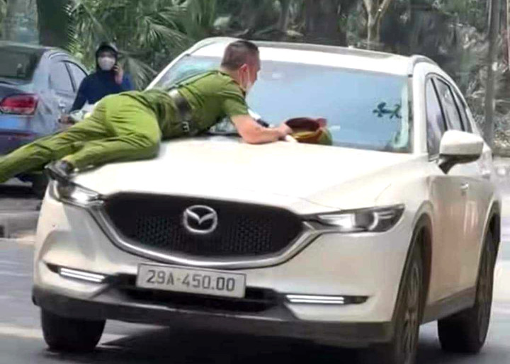 Cảnh sát bám trên nắp capo. (Ảnh cắt từ clip)