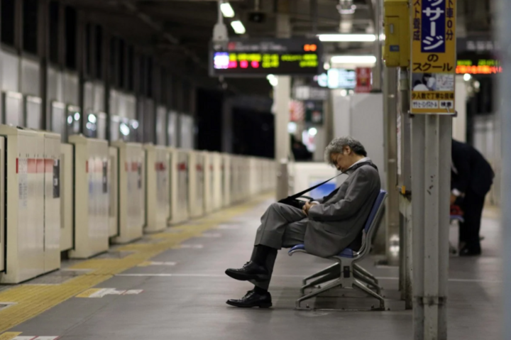 Một doanh nhân ngủ gật trên ghế ở ga xe lửa Tokyo, Nhật Bản. (Ảnh: SCMP)