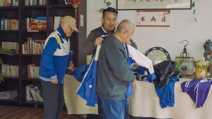 Feng Yan (giữa) giúp cư dân Jingya mặc đồng phục trước khi quay phim. (Ảnh: Theo Ding Rui/Sixth Tone)
