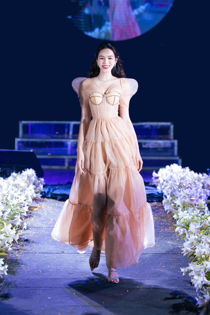 Ở vị trí vedette, Hoa hậu Đỗ Thị Hà xuất hiện trong sự ủng hộ nồng nhiệt của khán giả. Cô diện chiếc váy tay bồng đính kết hàng trăm viên đá cao cấp. Hoa hậu Việt Nam 2020 sải bước trên sàn runway như một đóa hoa đang nở rộ, khoe nhan sắc tuổi 23.