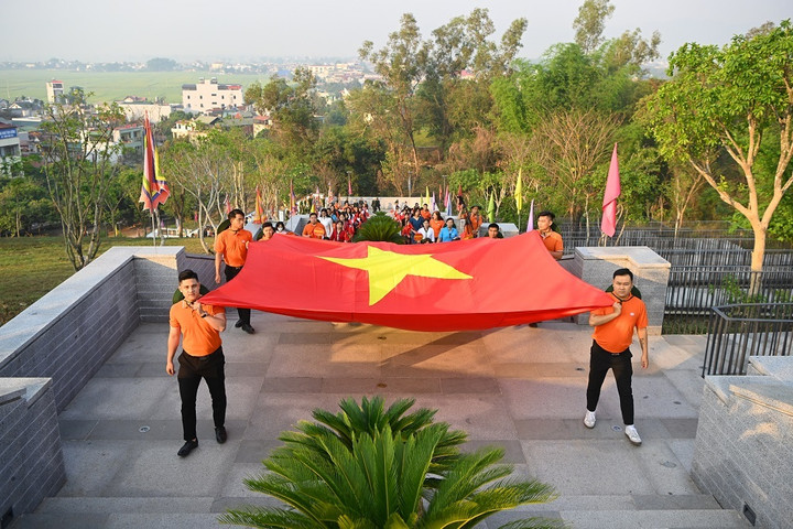 Cán bộ nhân viên tập đoàn FPT rước cờ Tổ quốc vào Đền thờ Liệt sĩ tại chiến trường Điện Biên Phủ. (Ảnh: Giang Huy)