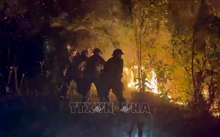 Đến 21h ngày 30/4, đám cháy vẫn chưa được khống chế, các lực lượng tham gia chữa cháy đang tập trung phát đường băng cản lửa, không để đám cháy lan rộng. (Ảnh: TTXVN phát)