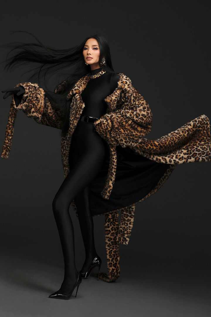 Kiểu mốt vợ ông trùm còn thể hiện đậm nét qua cách phối trang sức kim loại bản lớn gồm bông tai và dây chuyền xích, gợi nhớ đến những người vợ thích phô trương vẻ ngoài giàu có và hào nhoáng trong những năm 80. Trong set đồ màu tối, người đẹp 32 tuổi càng thu hút hơn với tông trang điểm màu nâu theo kiểu latin.