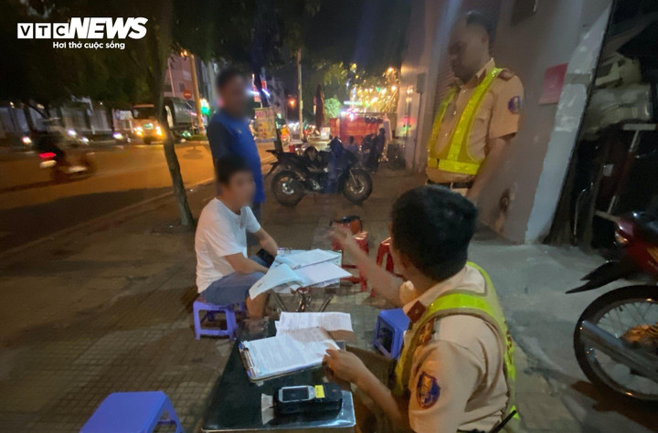 Ông M.T.H. (áo xanh) vi phạm nồng độ cồn kịch khung gọi bạn (áo trắng) đến chốt CSGT xin bỏ qua lỗi.