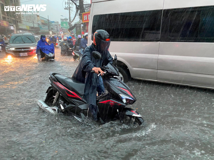 Người dân khó nhọc di chuyển giữa những sóng nước từ các xe ô tô tạo ra.