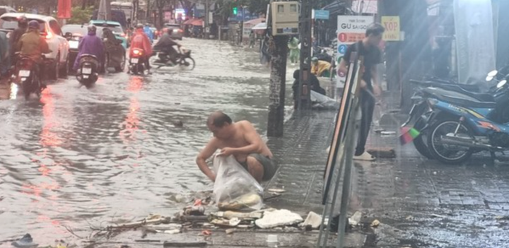 Người dân dọn rác trên các miệng thoát nước.