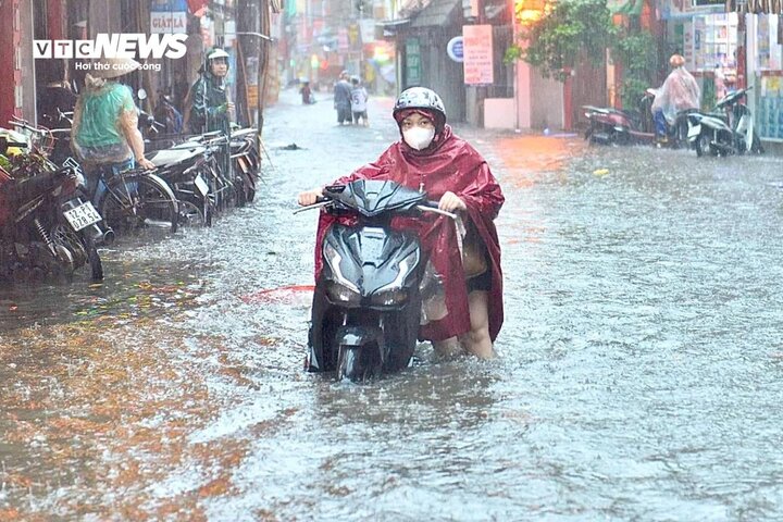 Người tham gia giao thông vật vã dắt xe bị chết máy giữa biển nước. (Ảnh: Ngô Nhung)