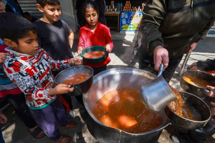 Trẻ em Palestine nhận khẩu phần thực phẩm nấu chín tại một điểm hoạt động thiện nguyện ở Rafah, phía nam dải Gaza. (Ảnh: SCMP)