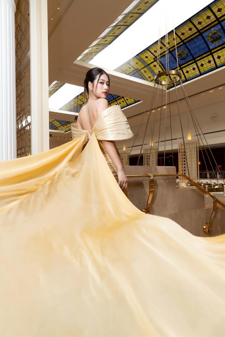 Thiết kế sử dụng chất liệu xuyên thấu mỏng kết hợp tông màu vàng gold đặc trưng của Miss Grand, phía sau có tà dài hàng mét để tăng độ lộng lẫy. Nhà thiết kế cùng đội ngũ mất 400 giờ làm việc để hoàn thiện các công đoạn, trong đó có khâu đính kết những hạt cườm liti tạo họa tiết hoa văn chạy khắp thân váy.