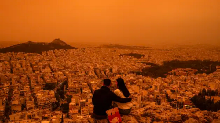 Một cặp đôi ngồi trên đồi Tourkovounia ở Athens, Hy Lạp khi những cơn gió phía nam mang theo làn sóng bụi Sahara đi qua khu vực, tháng 4/2024. (Ảnh: Getty)