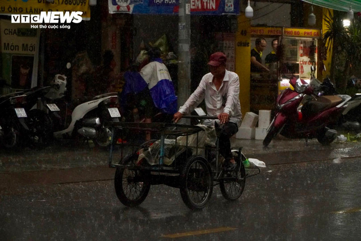 Người dân vất vả mưu sinh trong cơn mưa lớn.