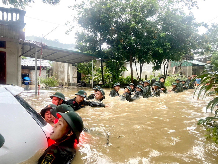 Cán bộ, chiến sĩ Bộ Chỉ huy Quân sự tỉnh dầm mình trong nước lũ giúp dân di chuyển ô tô khỏi dòng nước chảy xiết.