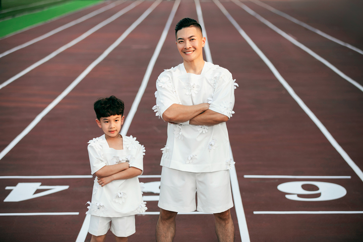 Nghệ sĩ Quốc Cơ cùng con trai bé Bắp xuất hiện trên sàn catlwak. Anh khiến khán giả thót tim khi bất ngờ có màn diễn xiếc ngắn cùng con. Bé Bắp tự tin trồng cây chuối trên hai tay của ba, khiến khán giả ồ lên thích thú.