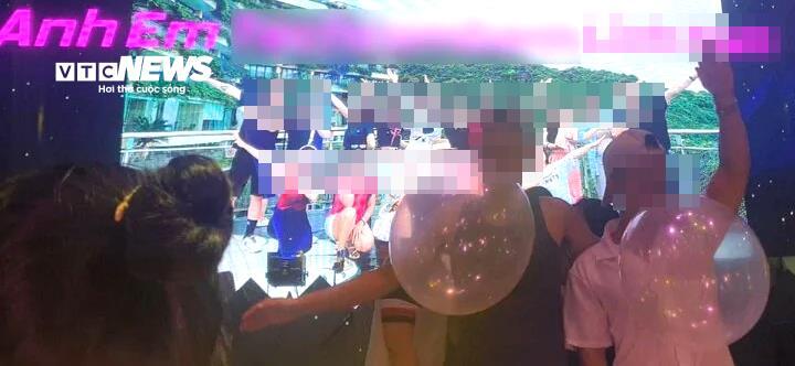 Trên sân khấu là các kỹ thuật viên DJ cùng những người đàn ông đang ngậm bóng cười lắc lư theo tiếng nhạc.