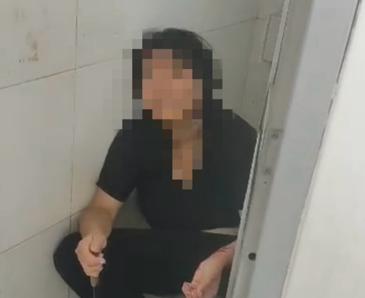 Cô gái ngồi trong nhà vệ sinh với con dao trên tay. (Ảnh: B.H)