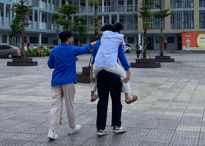 Tại điểm trường THCS Phú Thượng (Tây hồ), hai thanh niên trong đội tình nguyện nhiệt tình cõng một nữ sinh đau chân từ cổng trường vào phòng thi.