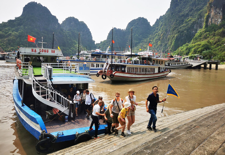Khách nước ngoài rời tàu lên tham quan hang động trên vịnh Hạ Long. (Ảnh: Báo Quảng Ninh)