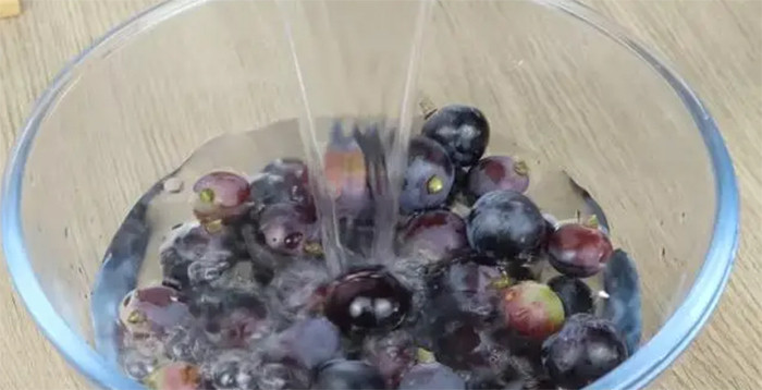 Sau khi ngâm nho xong, nên xả lại dưới vòi nước để tiếp tục làm sạch. (Ảnh: Sohu)