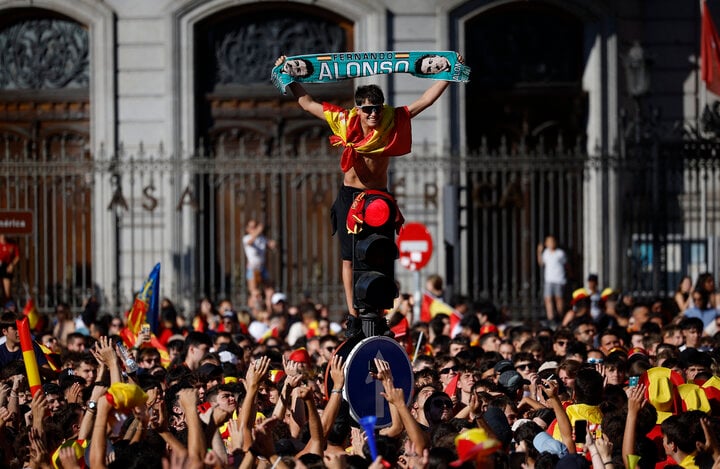 Một cổ động viên trèo lên cột đèn giao thông, khoe tấm khăn in hình Fernando Alonso - tay đua Formula 1 người Tây Ban Nha.
