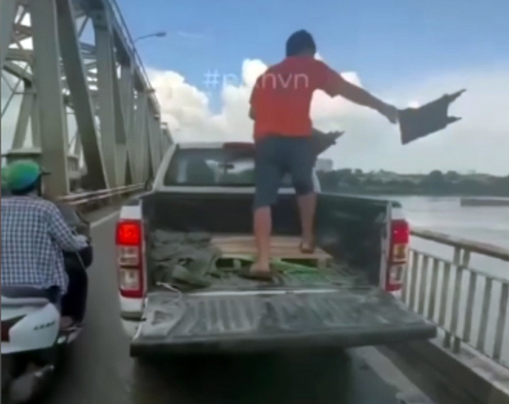 Ô tô bán tải dừng giữa cầu Chương Dương để người đàn ông ném rác xuống sông Hồng. (Ảnh cắt từ clip)