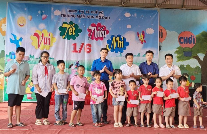 Ông Nguyễn Bá Quân, Phó Chủ tịch Thường trực UBND thị xã Quế Võ cùng các đồng chí trong đoàn trao quà cho các em học sinh có hoàn cảnh khó khăn xã Mộ Đạo.