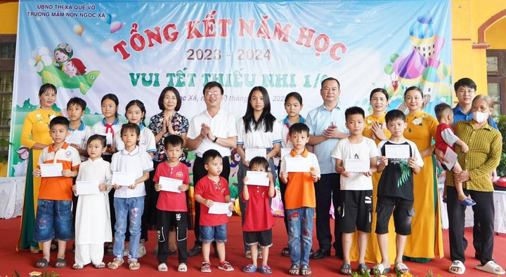 Ông Nguyễn Đức Lợi, Phó bí thư thị ủy Quế Võ (đứng thứ 2 từ phải qua) trao tặng 15 suất quà của thị xã cho các em có hoàn cảnh khó khăn tại xã Ngọc Xá.