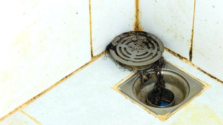 Cặn bã từ việc tắm rửa, tóc và các mảnh vụn khác nếu không được dọn dẹp thường xuyên sẽ tích tụ và phân hủy, khiến phòng tắm nặng mùi vào mùa hè. (Ảnh: The Spruce)